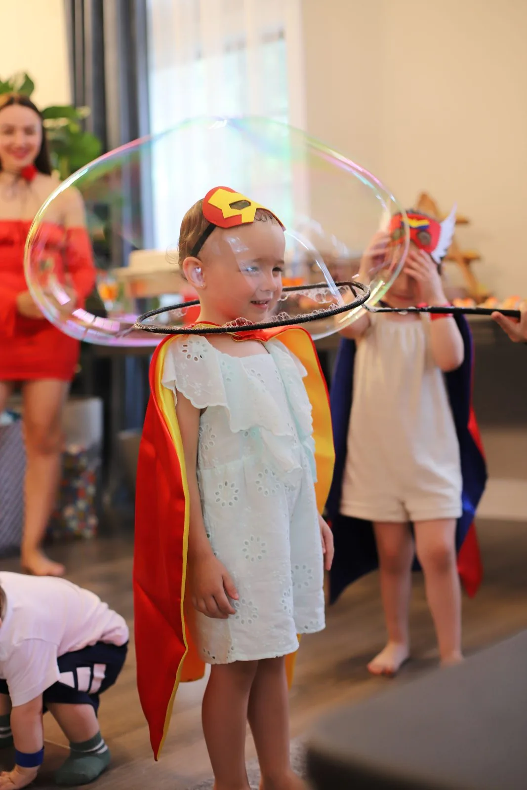 Girl in superhero cape inside a giant rainbow bubble