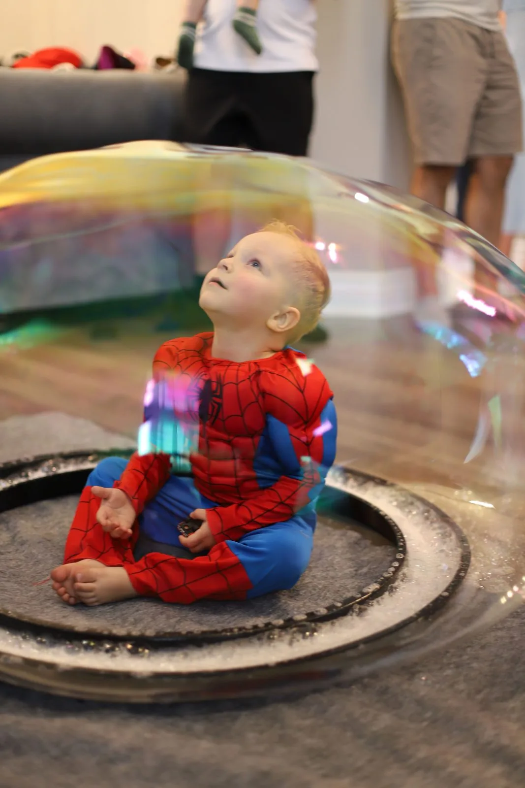 Child in Spider-Man costume sitting inside a giant bubble