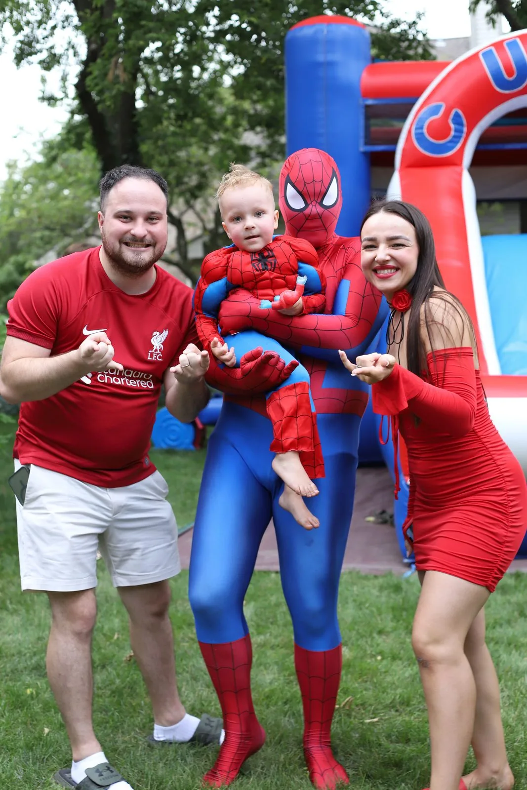 Family hugging Spider-Man at backyard birthday