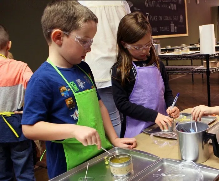 Kids in goggles pouring candle wax at a workshop