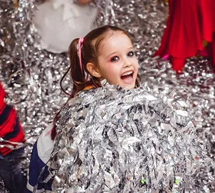 Smiling girl in shower of silver paper confetti