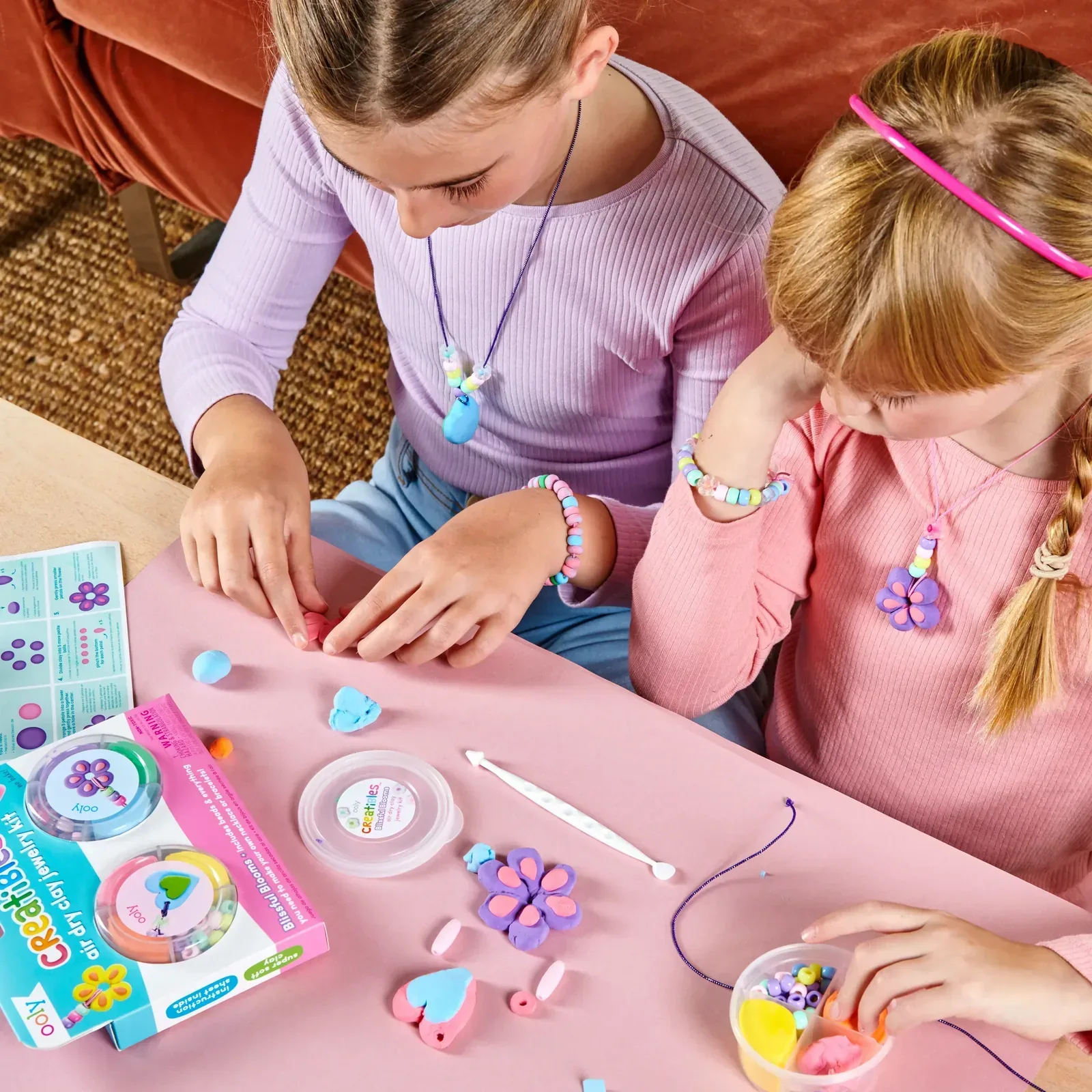 Two girls making polymer clay jewelry with bracelets and pendants
