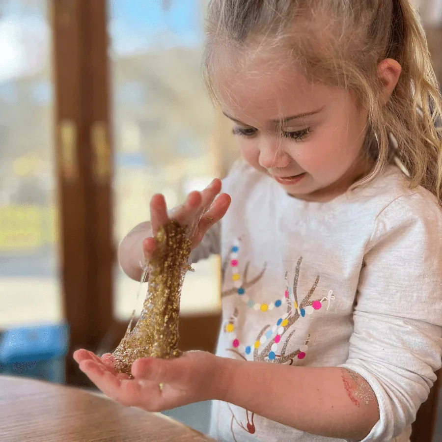 Little girl playing with golden glitter slime